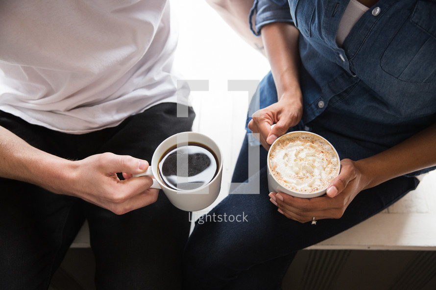 a couple holding  mugs of hot cocoa 