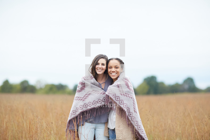 friends hugging under a blanket 