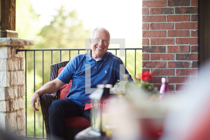 a smiling man sitting on a porch 