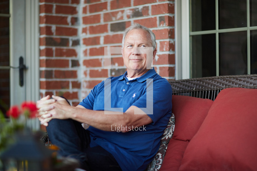 a smiling retiree sitting on a porch relaxing 