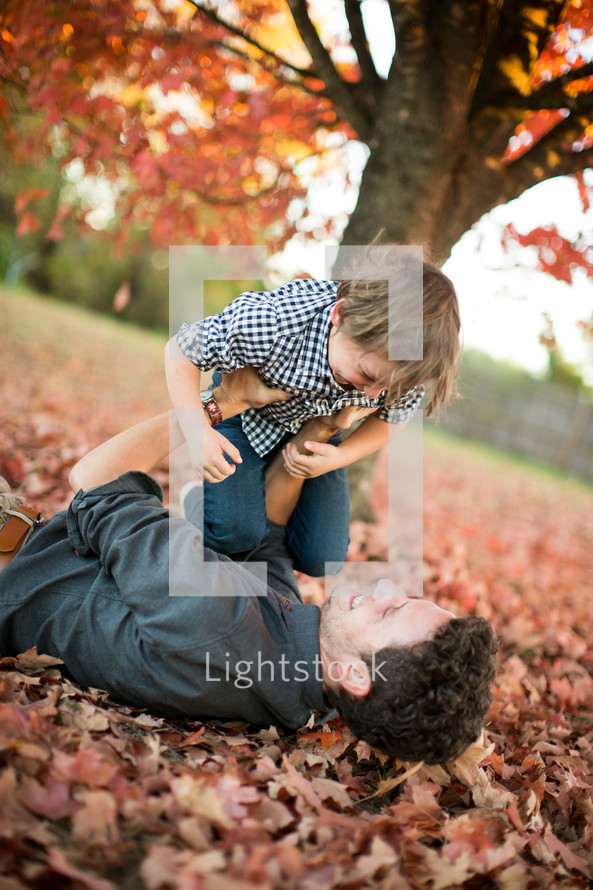 father and son playing in fall leaves 