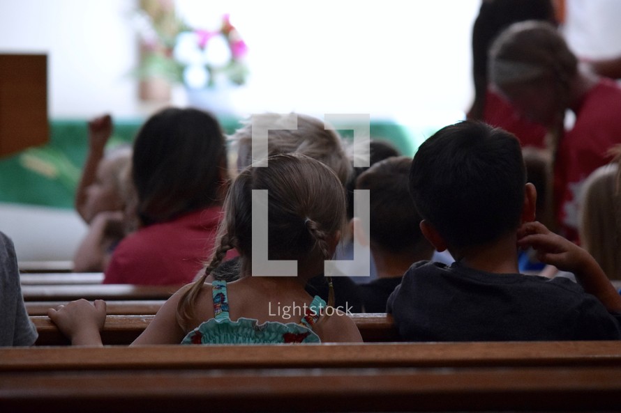 children listening sitting in church pews 