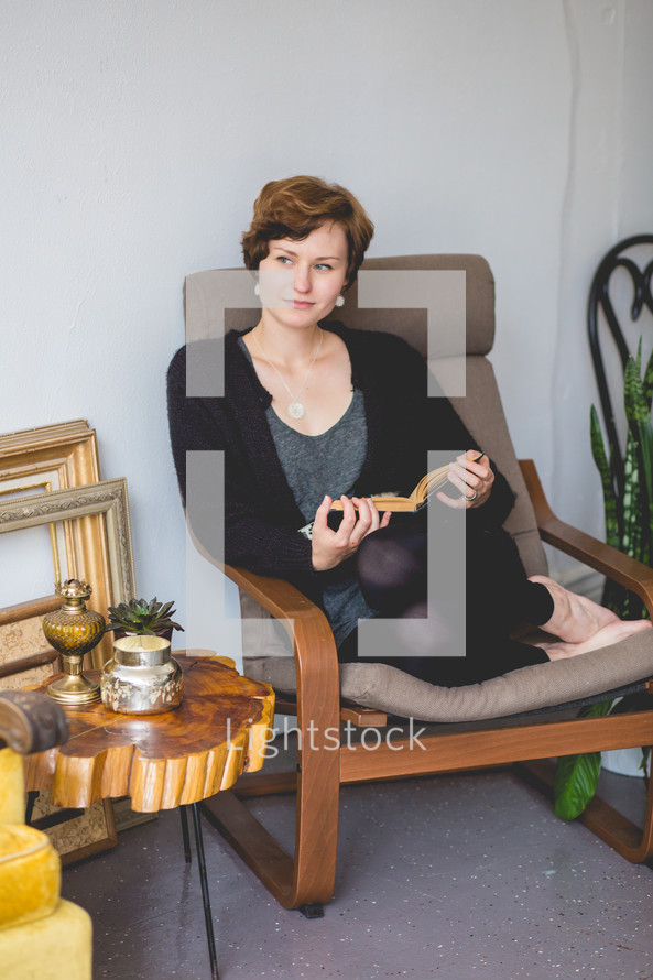 a woman sitting in a chair reading a book 