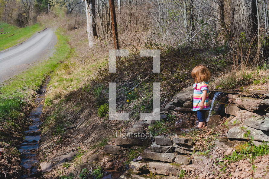 a little girl standing in a stream 