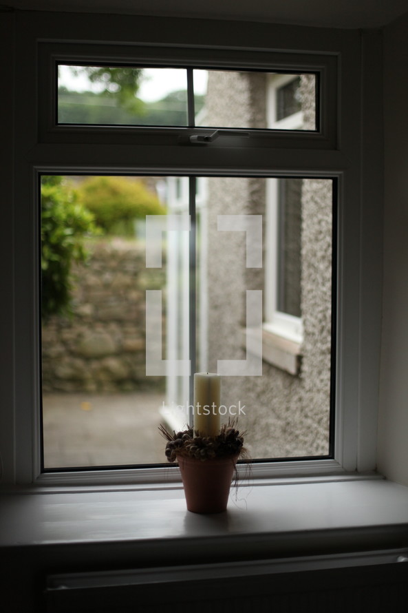 candle in a flower pot in a window sil 