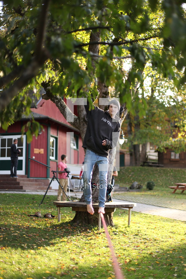 man balancing on a pole with hanging from a tree 