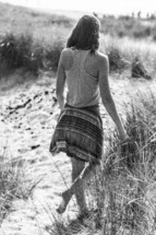 woman walking barefoot in the sand 