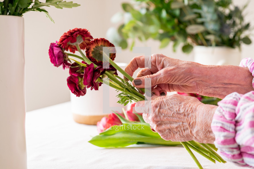 a senior woman arranging a bouquet of flowers 