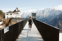 person walking across a bridge in a mountain town in Austria 