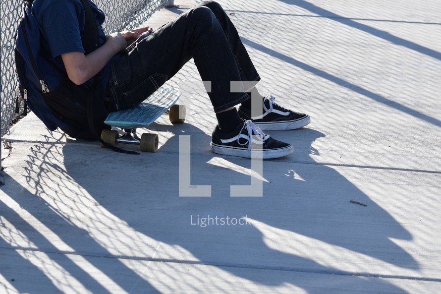 a boy sitting next to his skateboard 