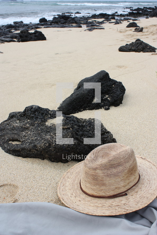 hat and rocks on a beach 