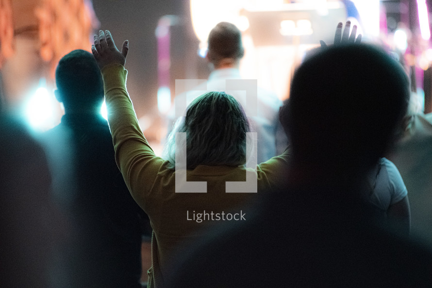 woman at a worship service with hands raised 