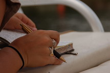 A woman's hands holding a book and pen.