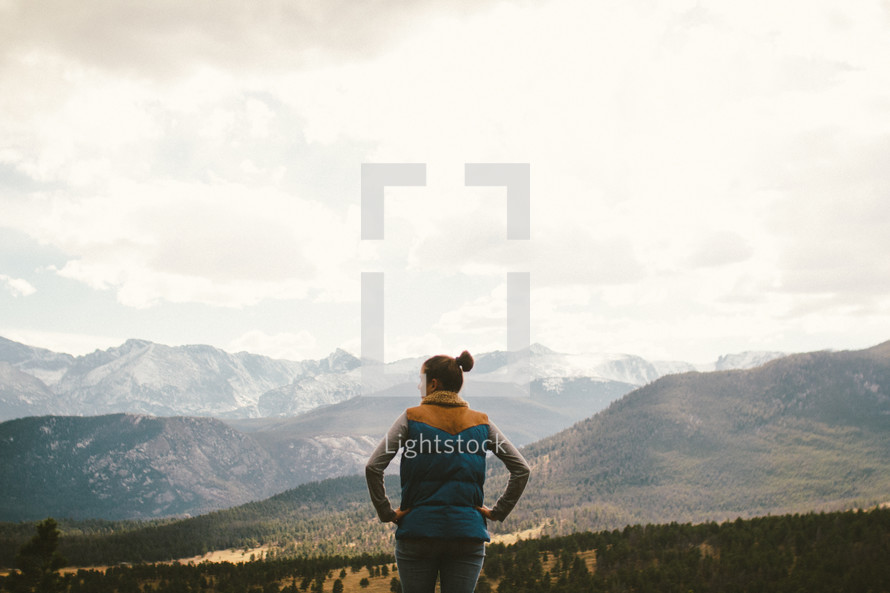 woman with hands on her hips standing on a mountain 