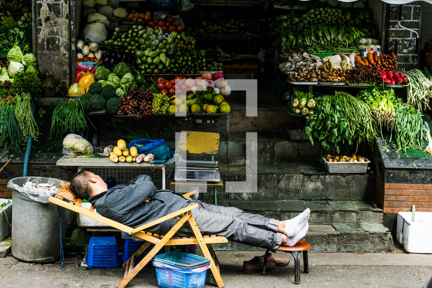 man resting at a produce market in China 