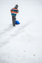 child digging with a shovel in snow 
