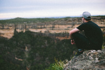 Man sitting on the edge of a canyon.