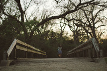 woman walking across a wooden footbridge in  a park 