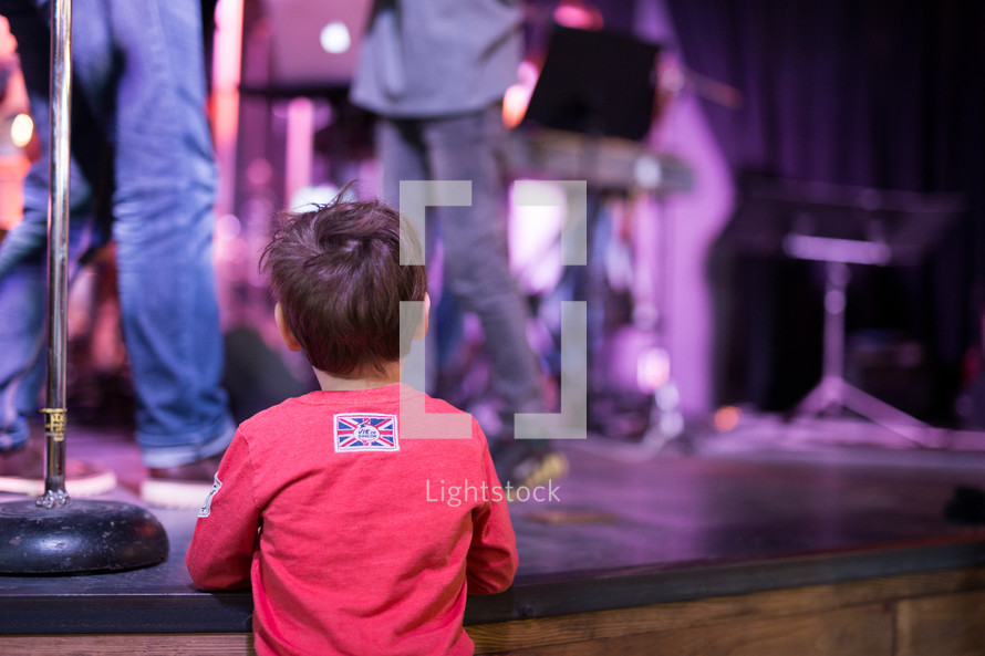 a child watching musicians perform on stage 