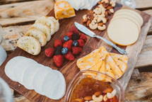 A wooden cutting board covered with a variety of appetizers.
