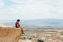 a man sitting at the edge of a cliff in Cappadocia
