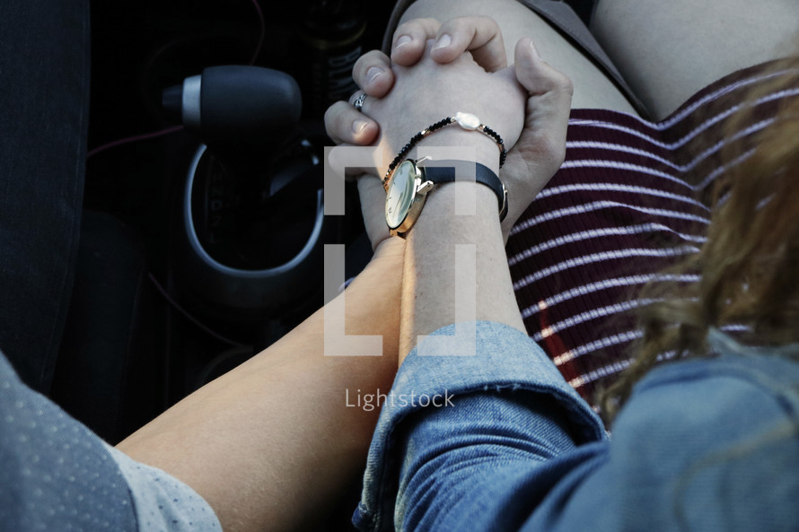 a couple holding hands in a car 