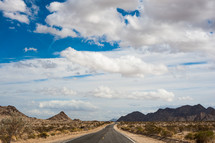 highway through desert and mountains - cloud filled sky