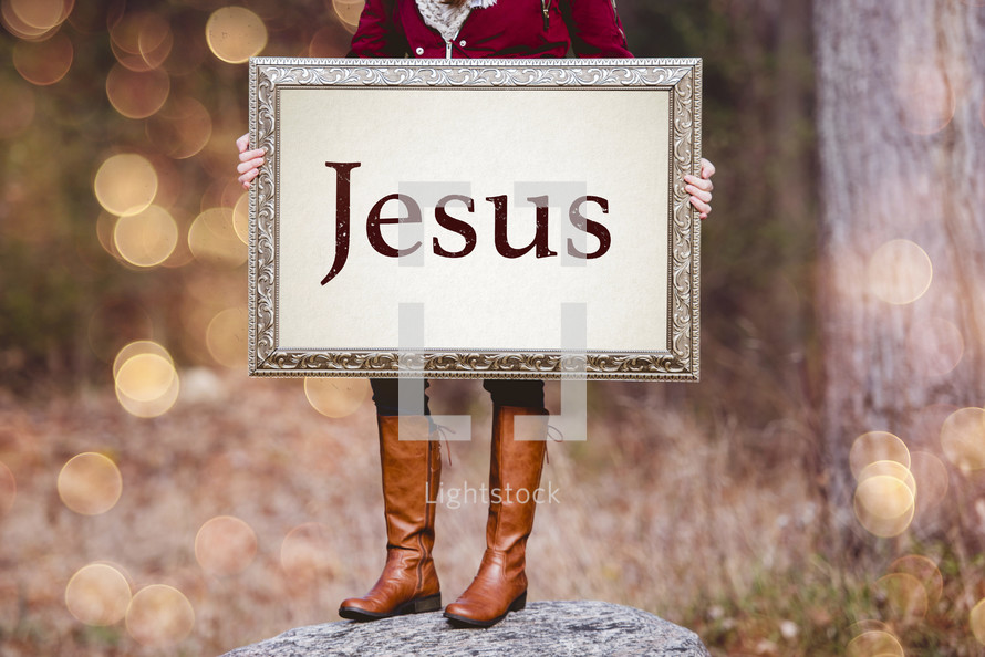 a woman holding a sign the reads Jesus 