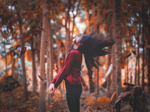 a woman flipping her hair in a fall forest 