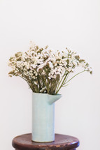 white flowers in a vase on a stool 