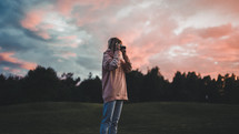 a woman taking a picture at sunset 