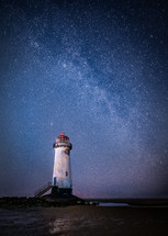 lighthouse under stars in the night sky 
