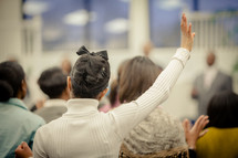 woman raising her hand in praise at a worship service
