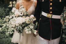 a woman in a wedding dress and a man in a military uniform hold hands