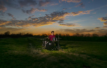 drummer playing in a field at sunset 