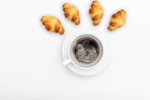 white cup with coffee on a white background with french croissant and place for text