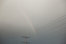 rainbow in an overcast sky over power lines 