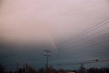 rainbow in an overcast sky over power lines 