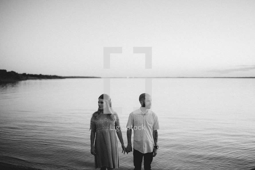 a couple holding hands along a shore 