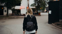 a young woman walking towards an outdoor restaurant 