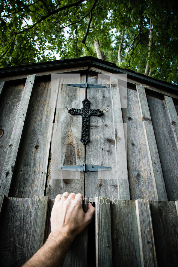 Opening the door to a wooden barn with a cross