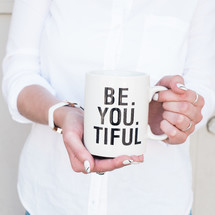 woman holding a mug with the words Be. You. Tiful. 