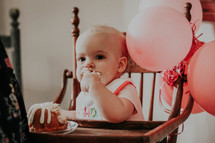 an infant in a high chair eating cake 