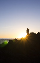 silhouette of a couple kissing on a shore 