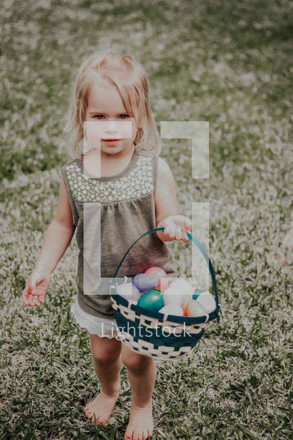 toddler girl carrying a basket of Easter eggs