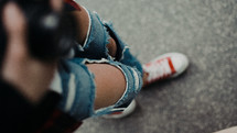 young woman in torn jeans and sneakers 