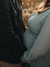 a pregnant woman and her husband hold hands