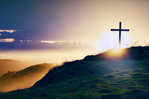 A cross on a hill in a sunset
