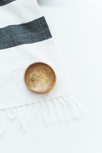 a wood bowl with paperclips on a striped scarf 