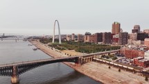 A railroad train coming into downtown Saint Louis, Missouri over the Mississippi River with skyscraper buildings in the background.